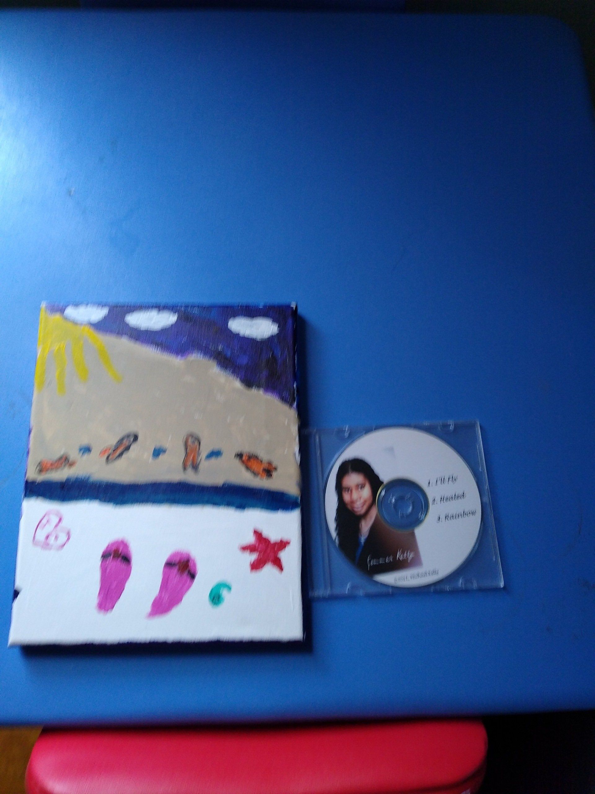 Canvas art of beach scene with a CD on a blue surface.