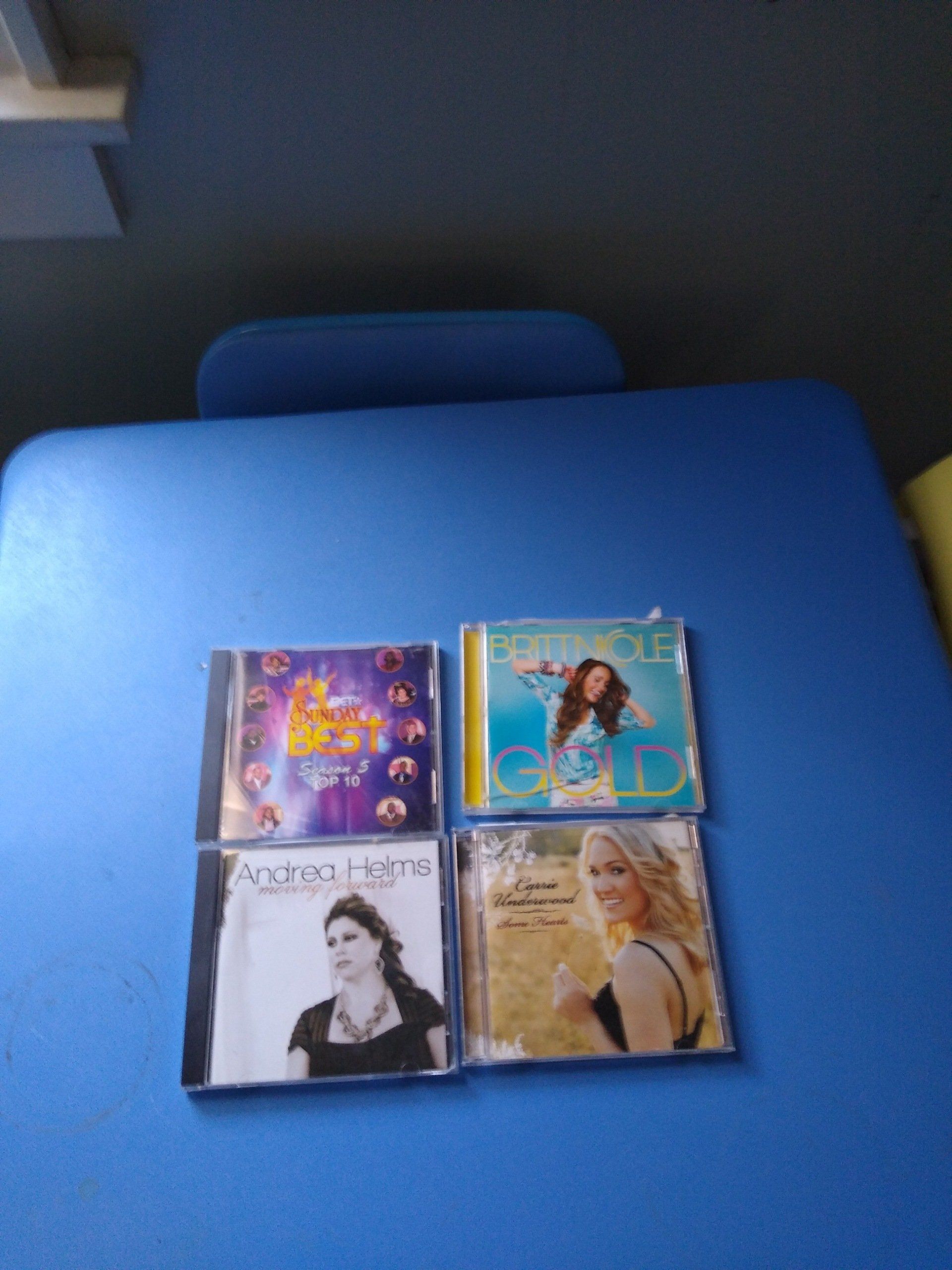 Four CDs on a blue surface; album covers feature colorful artwork and women's faces.