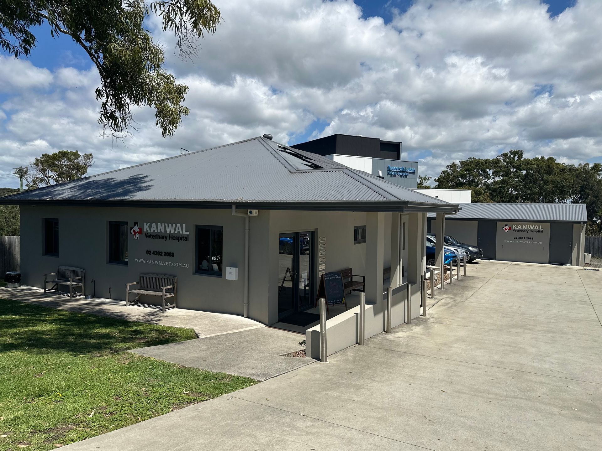 A large building with a gray roof is sitting on top of a lush green field. — Kanwal Veterinary Hospital In Kanwal, NSW
