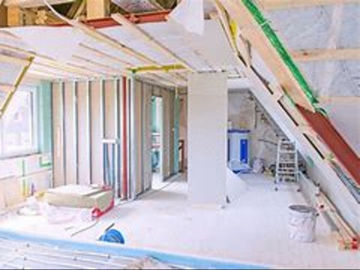 A room in a house under construction with a ladder in the corner .