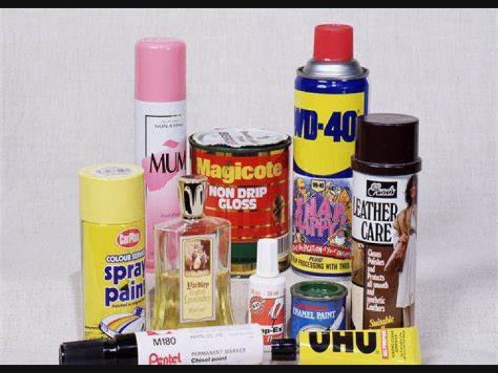 A group of bottles and cans of various types of cleaning products are sitting on a table .