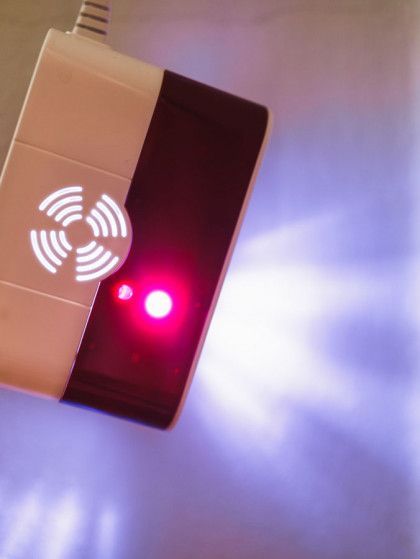 A close up of a smoke detector with a red light on it