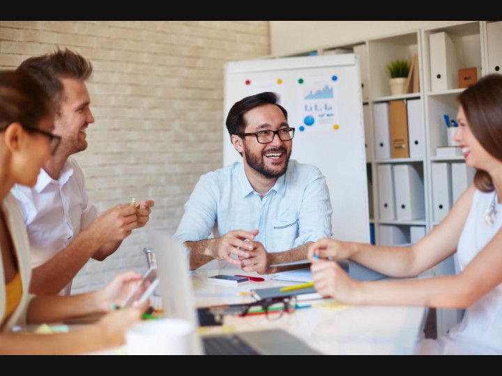 A group of people are sitting around a table and laughing