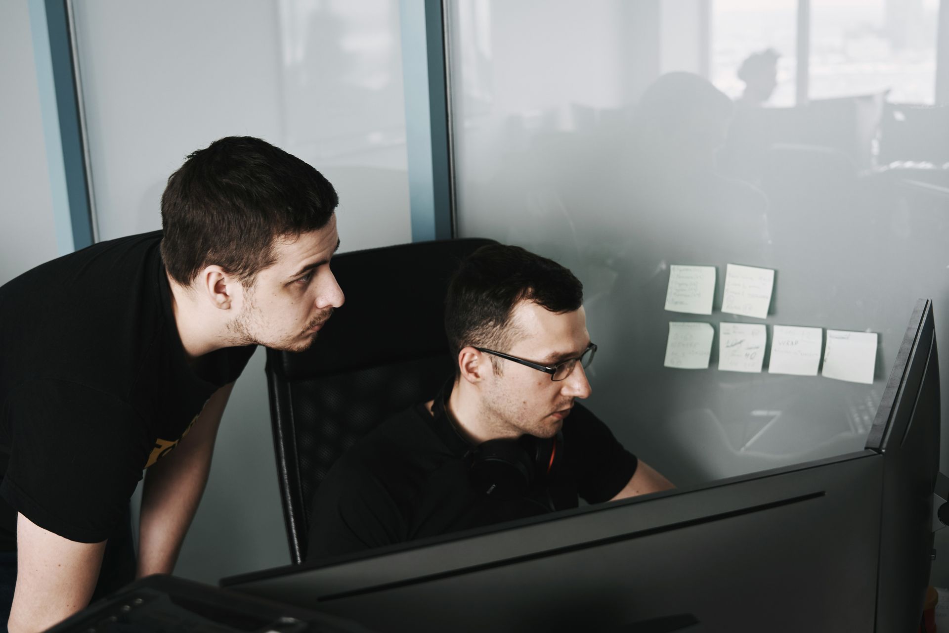 Two men are looking at a computer screen together.