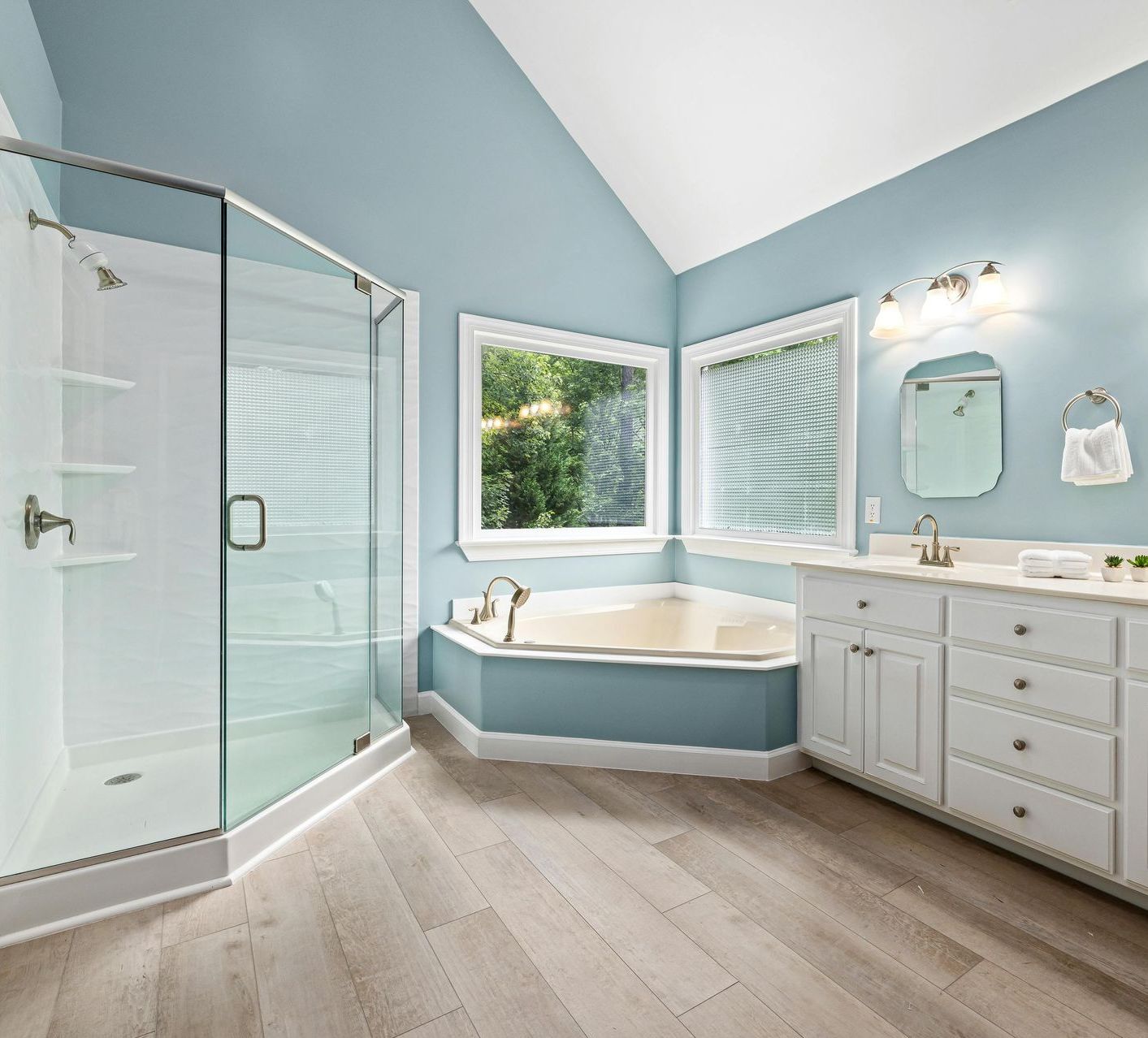 A bathroom with a tub , sink , shower and window.