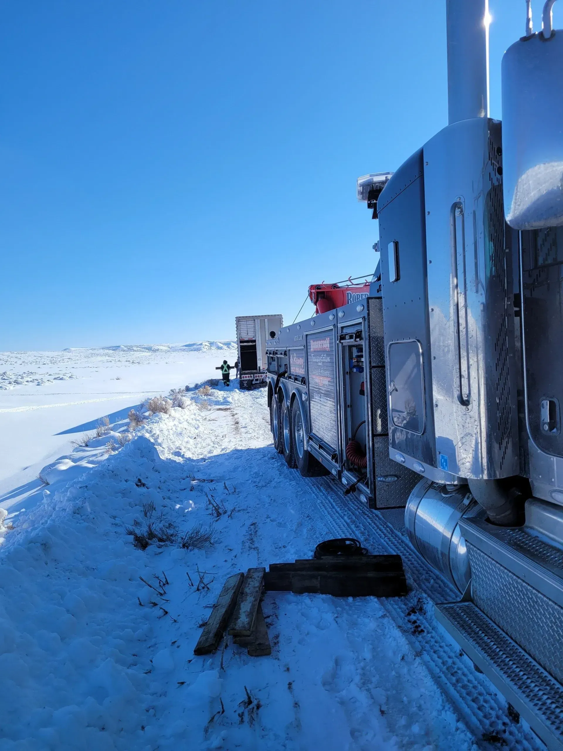 A truck is stuck in the snow on a snowy road — Evanston, WY — Robertson Transportation Inc. Towing and Recovery