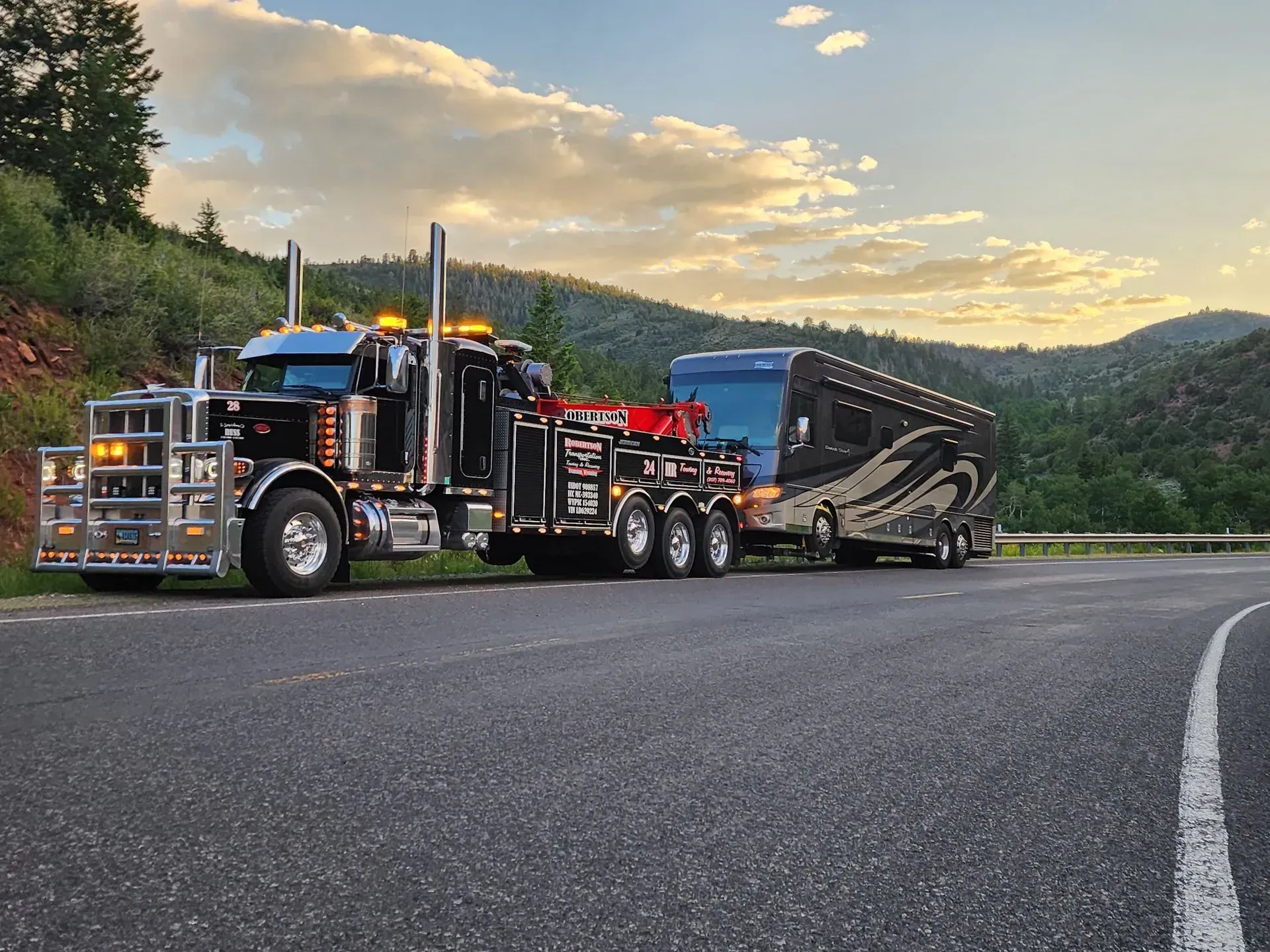 A tow truck is towing a rv down a road — Evanston, WY — Robertson Transportation Inc. Towing and Recovery