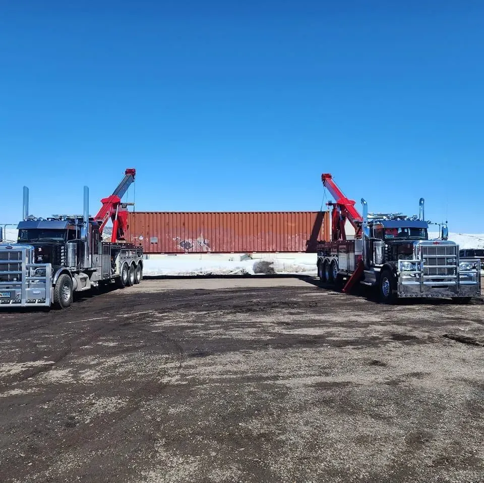 Two tow trucks are parked next to each other in a dirt field — Evanston, WY — Robertson Transportation Inc. Towing and Recovery