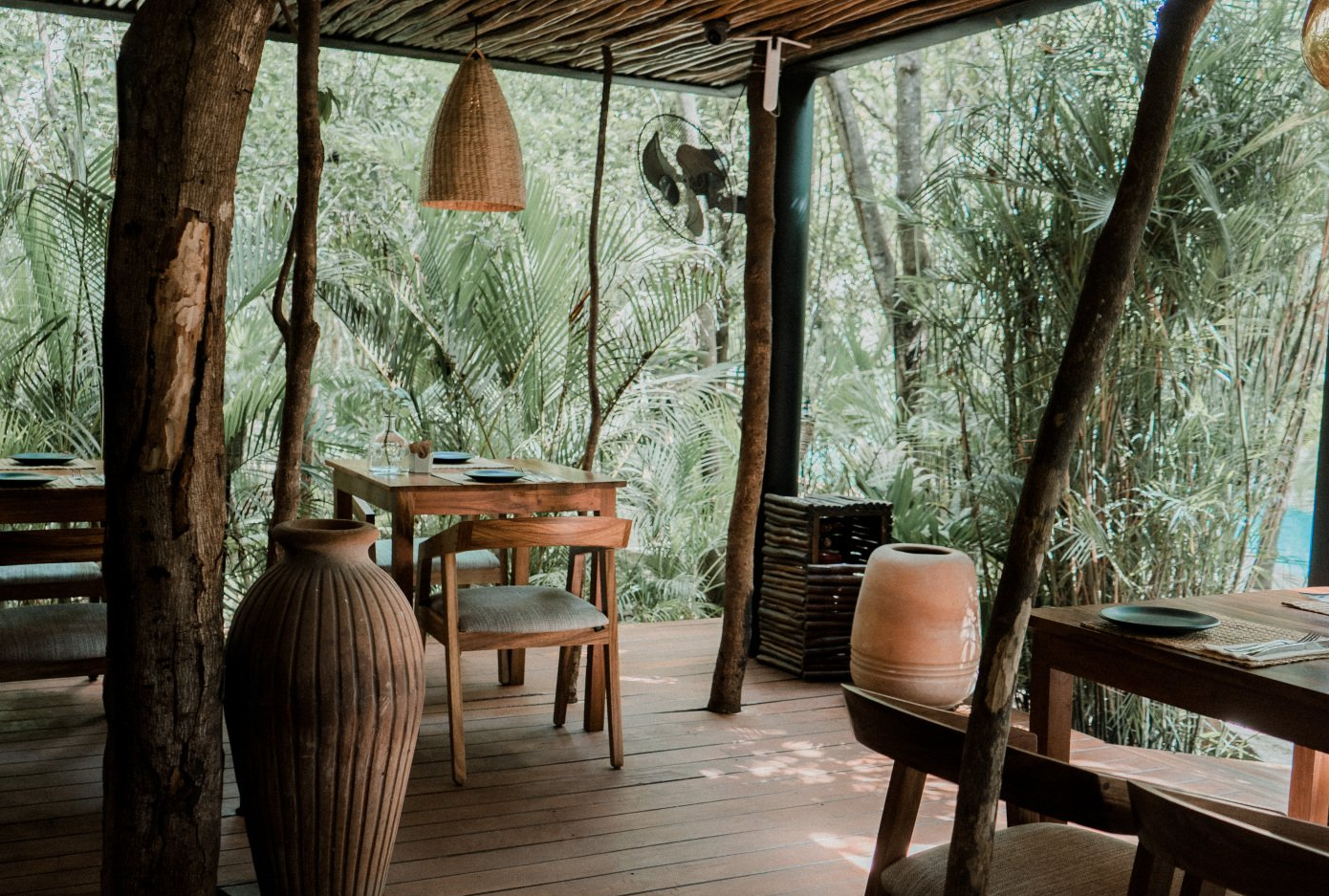 A patio with tables and chairs in the middle of a forest.