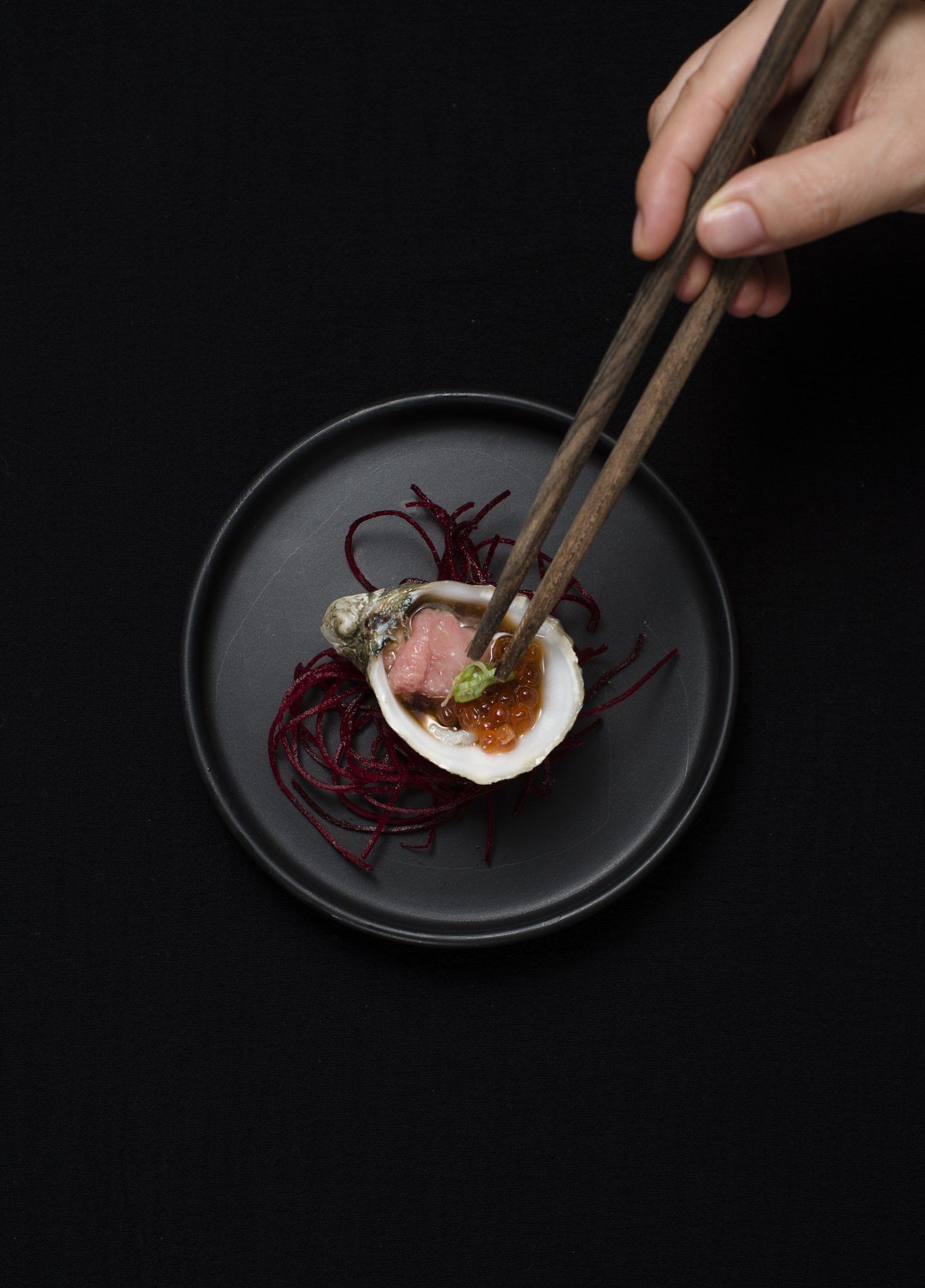 A person is holding chopsticks over a plate of food.