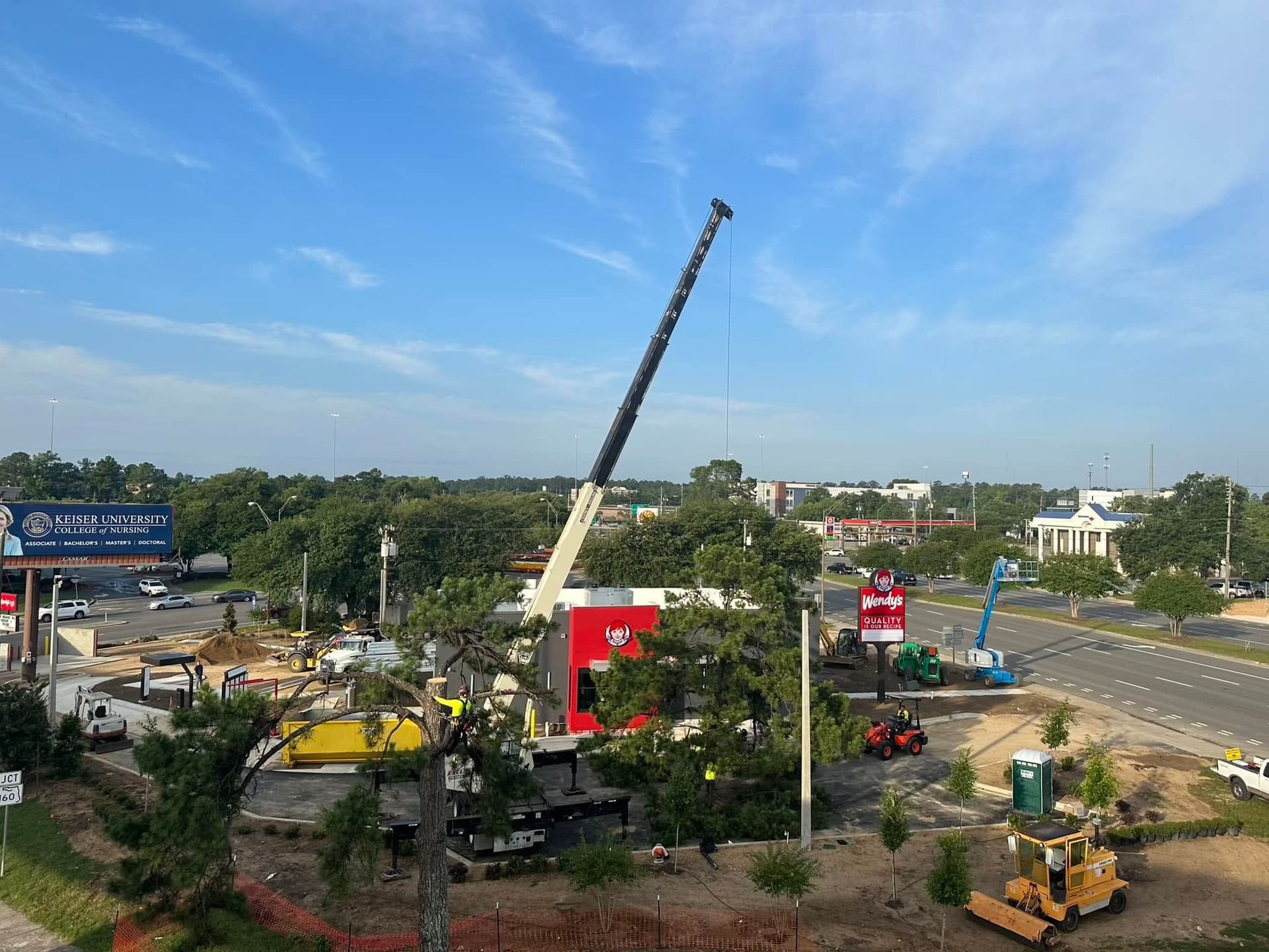 Construction site with crane lifting near a road under a blue sky