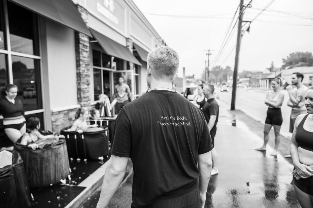 A man in a black shirt is walking down a sidewalk in front of a restaurant.