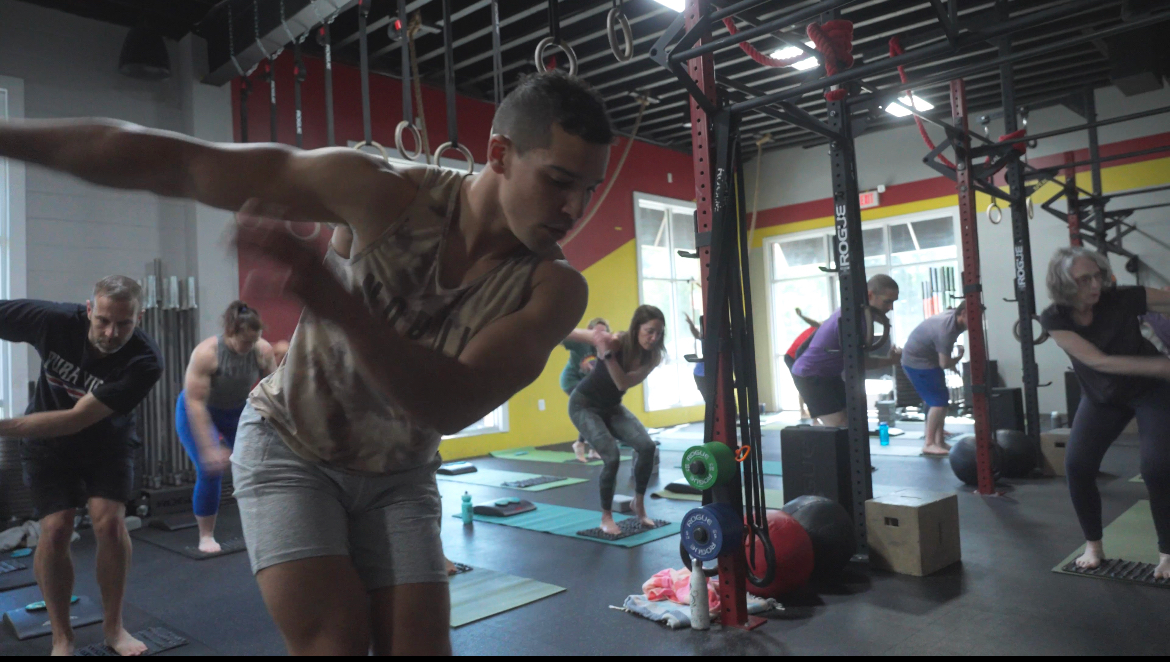 A group of people are doing yoga in a gym.