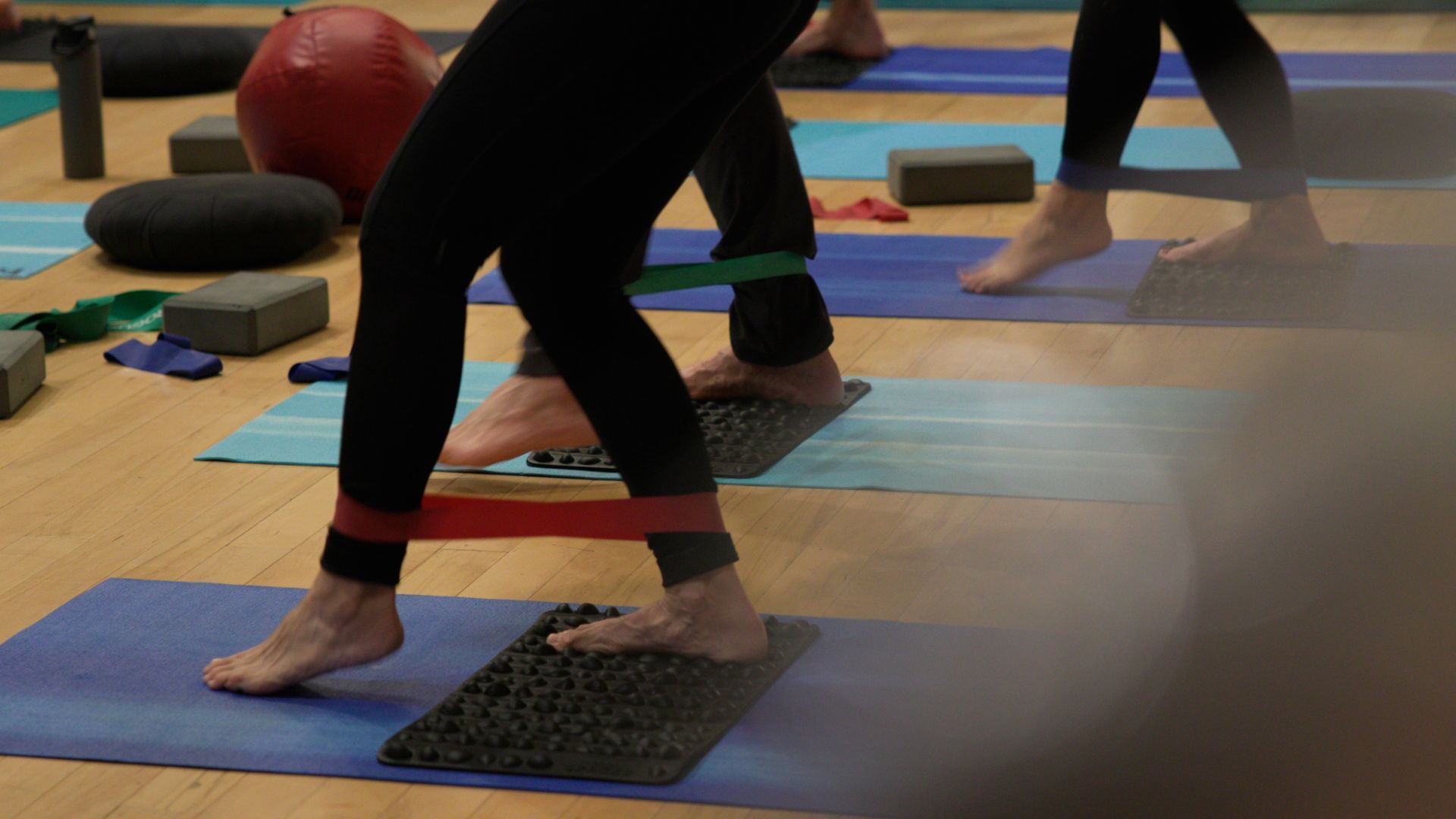 A group of people are doing exercises on yoga mats in a gym.