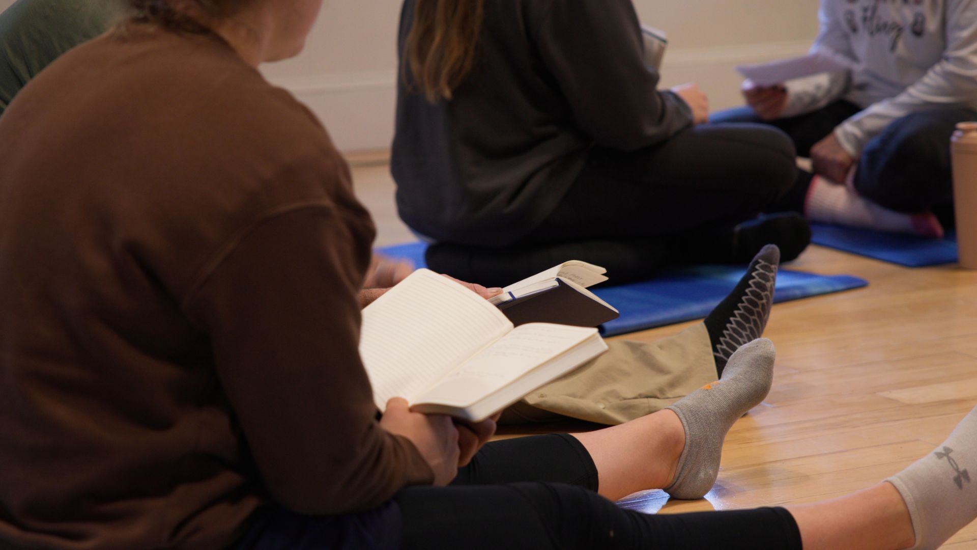 A group of people are sitting on the floor reading books.