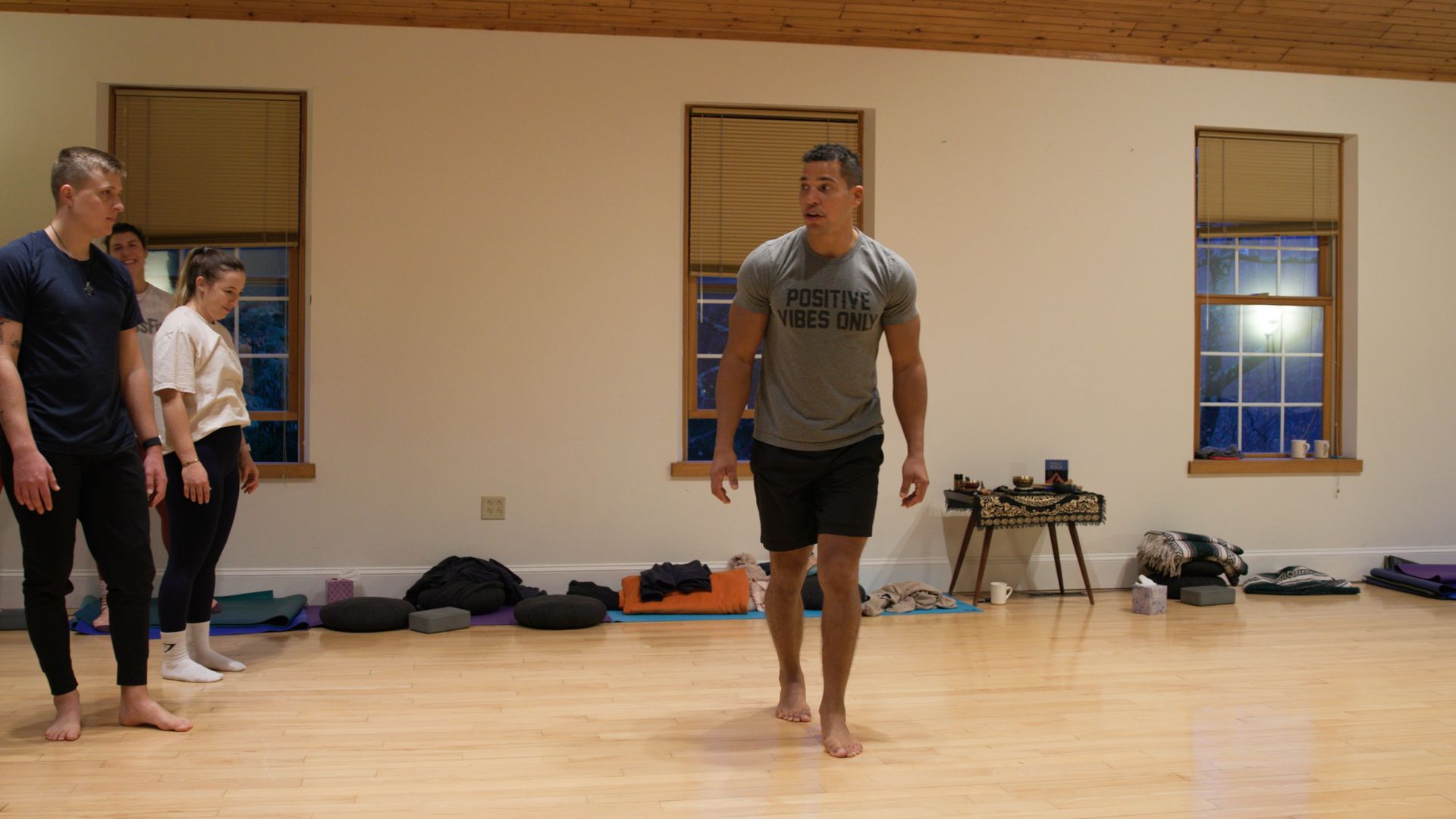 A group of people are standing on a wooden floor in a room.
