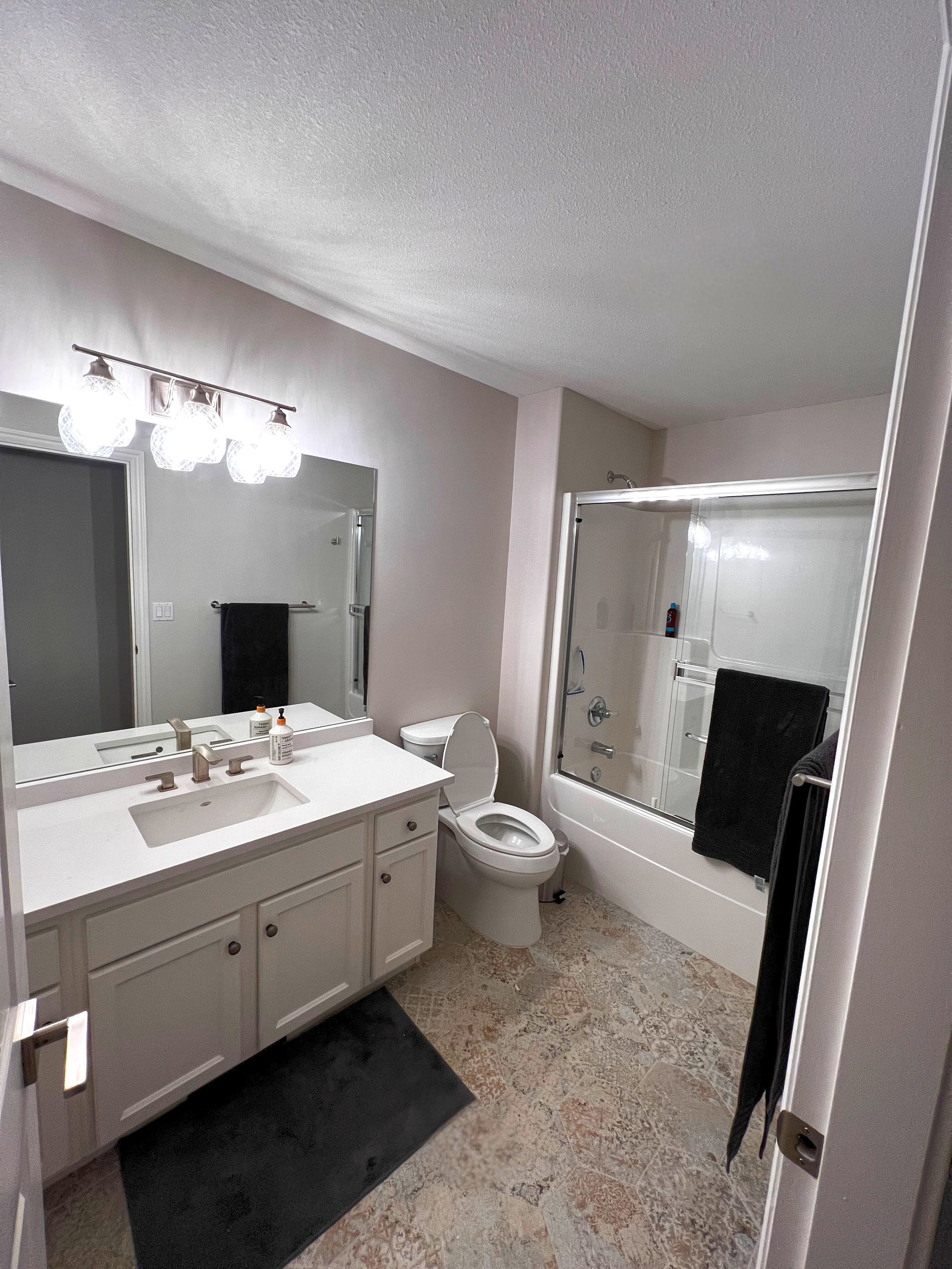 Bathroom with white vanity, mirror, toilet and tub/shower combo.