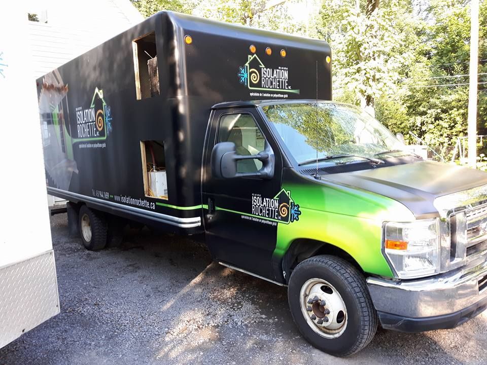 Camion-caisse noir et vert avec logo, stationné à l'extérieur.