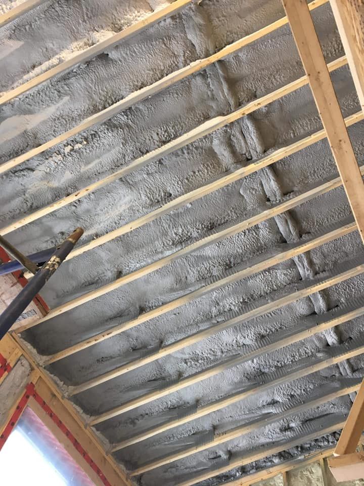 Chevrons en bois recouverts d'un isolant gris, formant un plafond dans un bâtiment en construction.