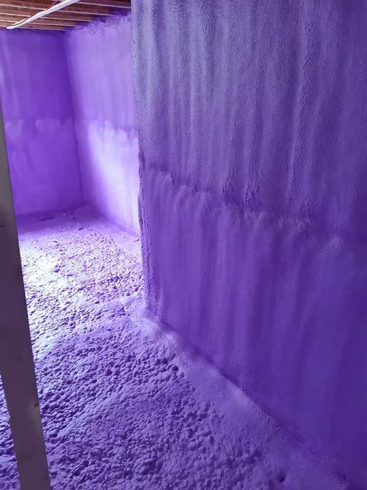 Une isolation en mousse pulvérisée violette recouvre les murs et le sol d’un sous-sol.