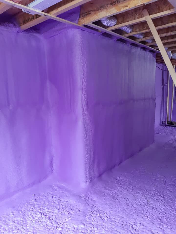 Isolation en mousse pulvérisée violette sur les murs et le plafond du sous-sol.