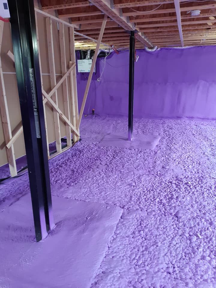 Sous-sol rempli d'isolant violet. Poutres et poteaux de soutien en bois visibles.