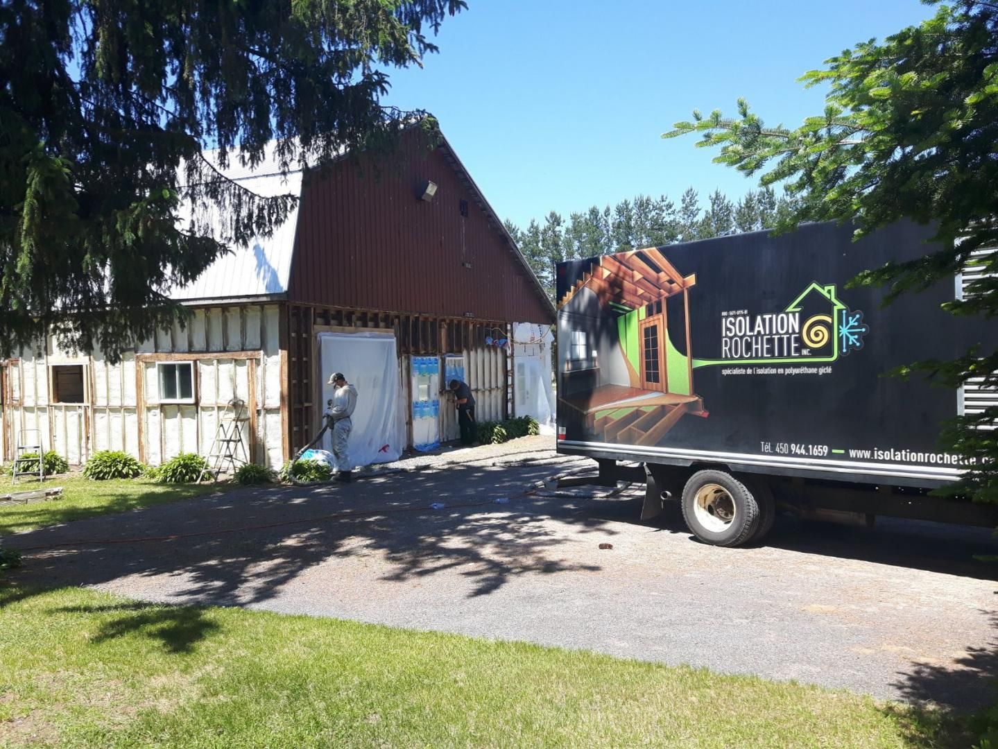 Camion de la société Insulation Solutions stationné près d'une grange en rénovation ; journée ensoleillée.