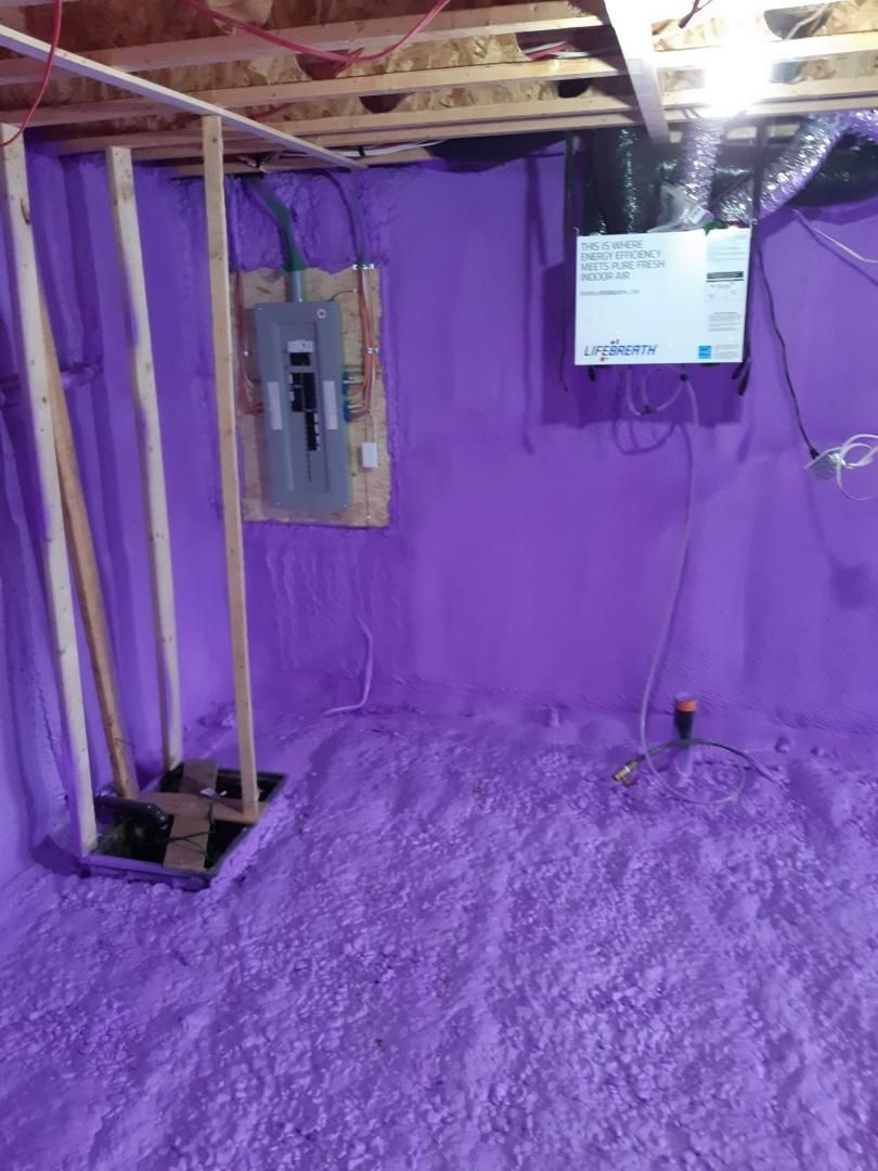 Murs de sous-sol isolés violets avec panneau électrique et câblage.