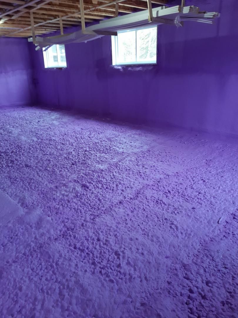Pièce intérieure peinte en violet avec un sol texturé ; deux petites fenêtres en hauteur sur le mur, plafond non fini.