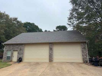 A large garage with two garage doors and a roof.
