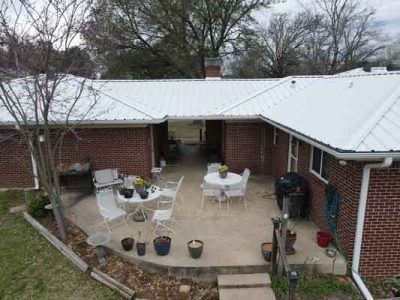 An aerial view of a brick house with a white roof and a patio with a table and chairs.