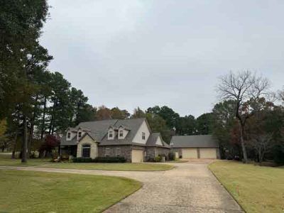 A large house with a driveway leading to it is surrounded by trees.