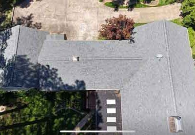 An aerial view of a house with a roof and a driveway.