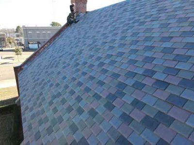 A man is sitting on the roof of a house.