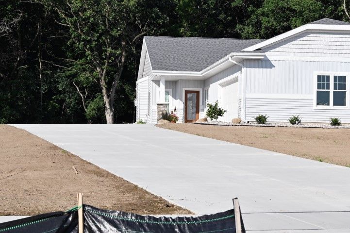 Light blue house with a concrete driveway; trees in the background.