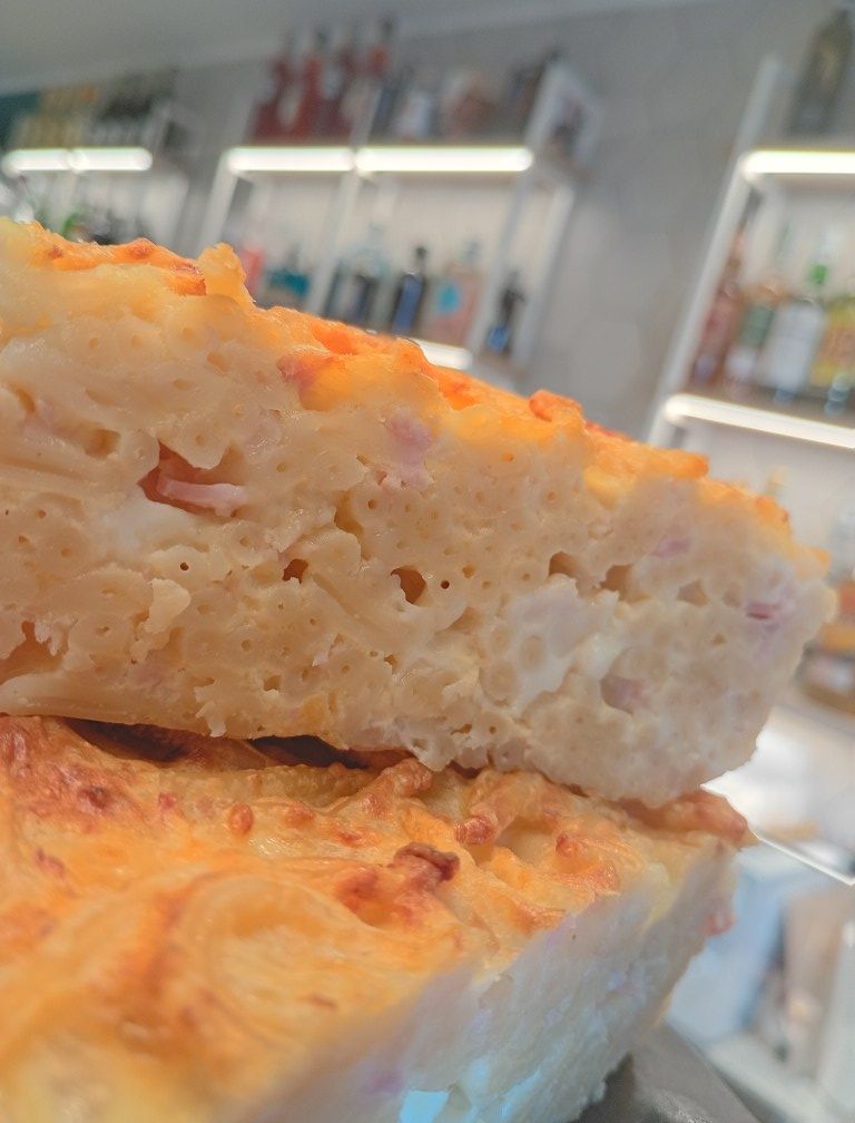 Primo piano di una fetta quadrata di focaccia, leggermente dorata, impilata su un'altra.