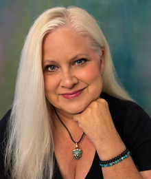 A close up of a woman 's face with blonde hair and a gray jacket.