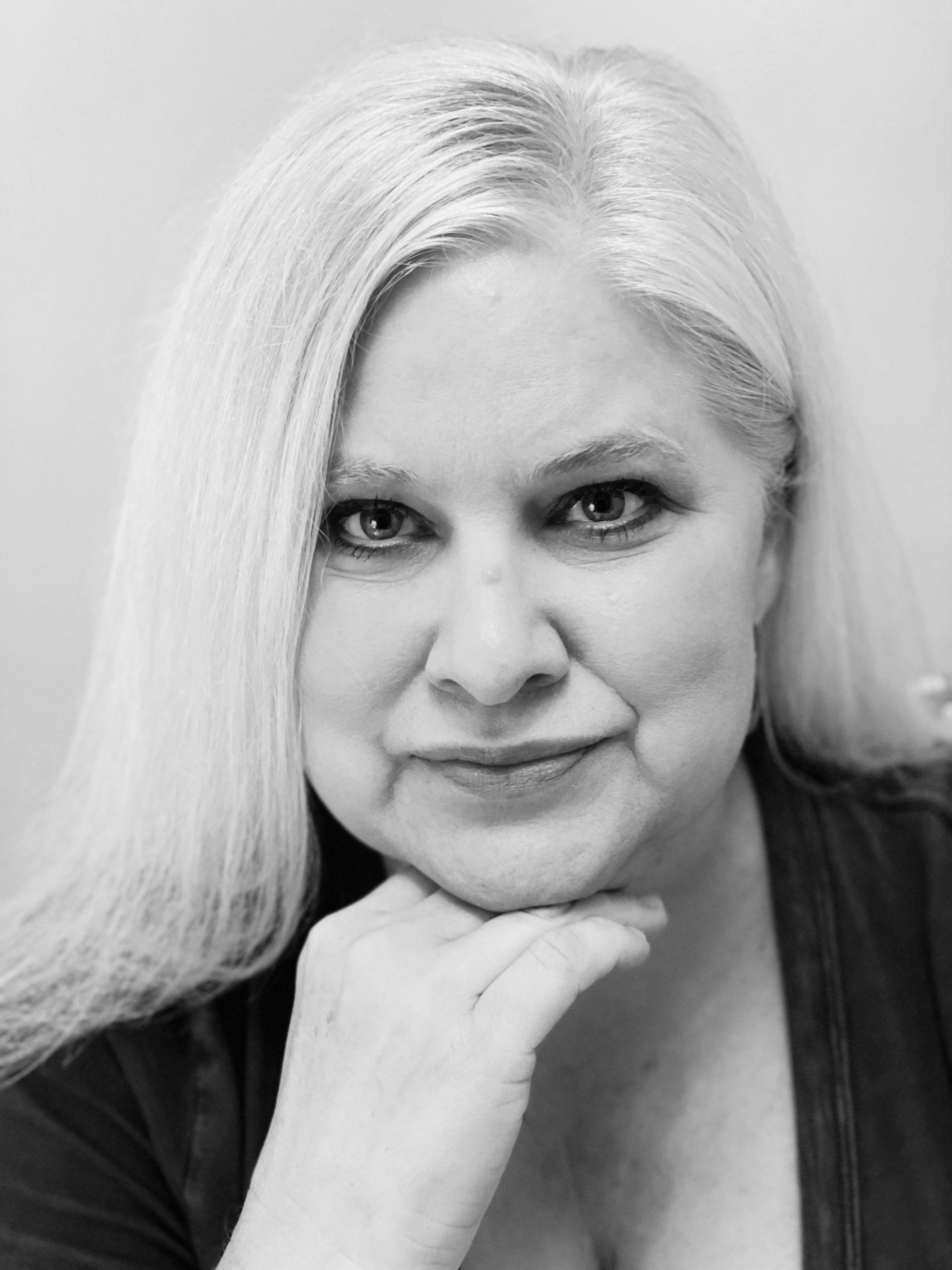 A black and white photo of a woman with her hand on her chin.