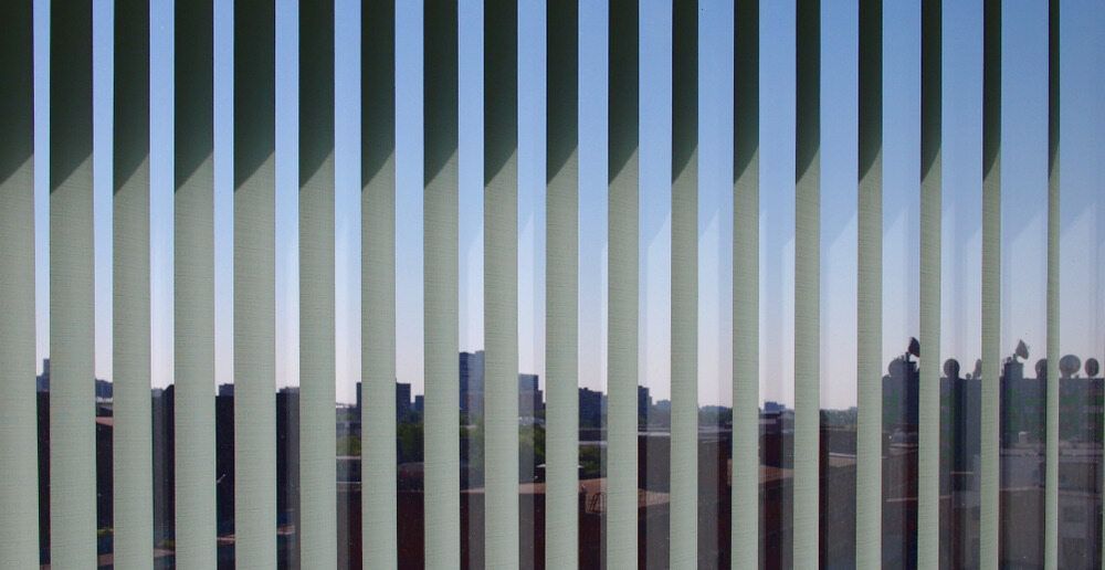 Partially open vertical blinds revealing a landscape in the background