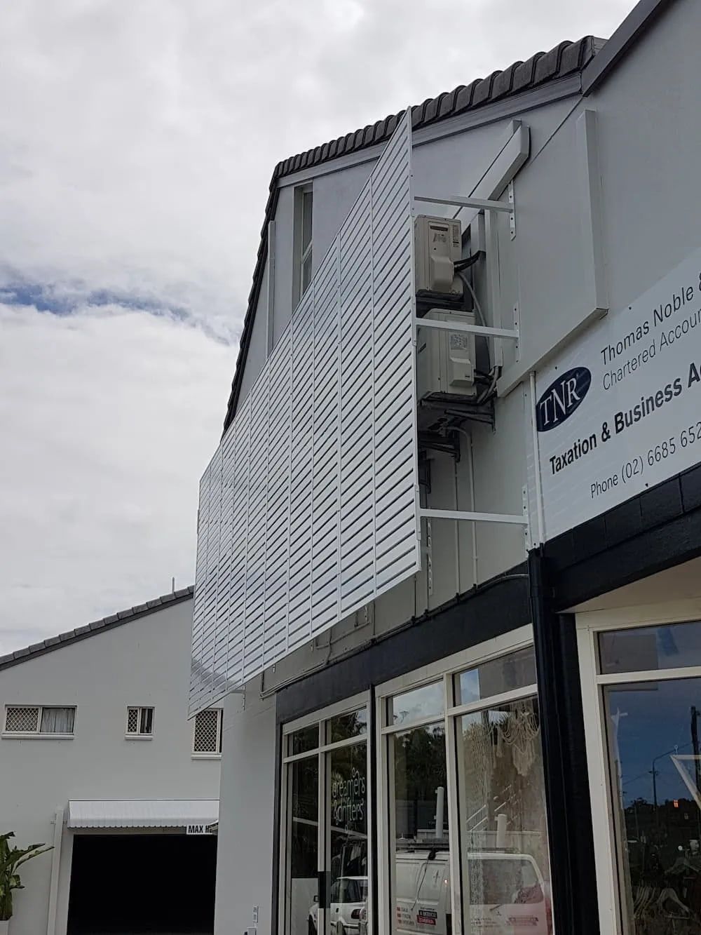 A White Building With A White Lattice On The Side Of It — Summerland Screens & Awnings In Ballina, NSW