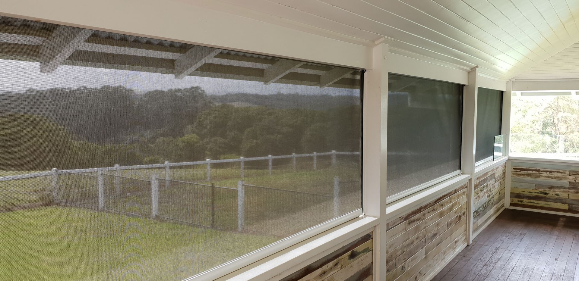 A Screened In Porch With A Blue Sectional Couch And A Coffee Table — Summerland Screens & Awnings In Ballina, NSW