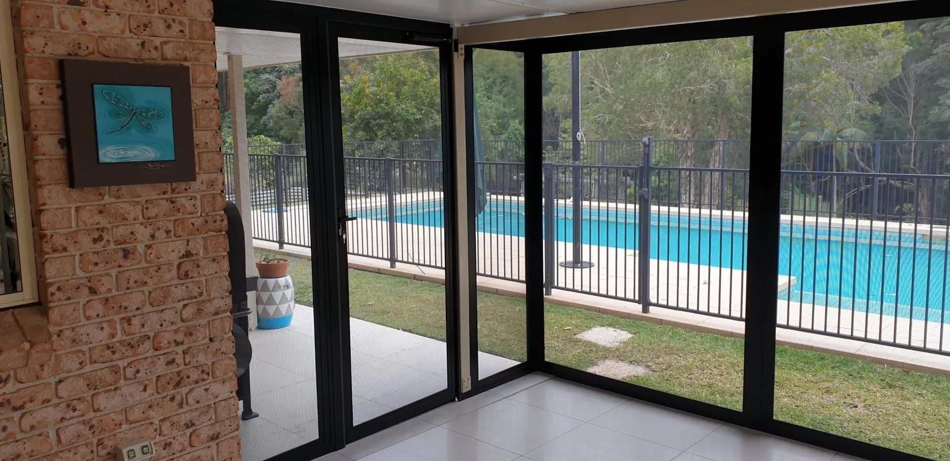 A Screened In Porch With A Swimming Pool In The Background — Summerland Screens & Awnings In Suffolk Park, NSW