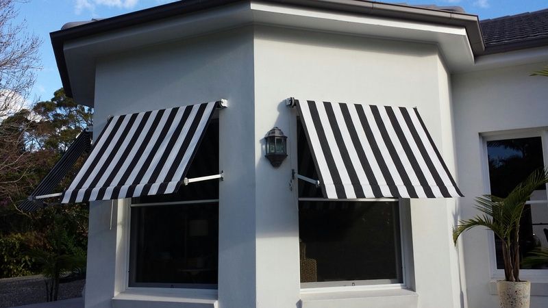 A White House With A Black And White Striped Awning Over A Window — Summerland Screens & Awnings In Ballina, NSW