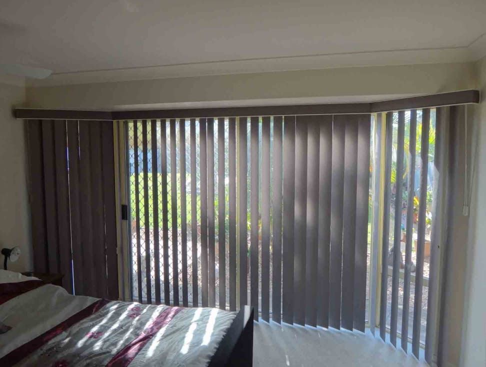 A Bedroom With A Bed And Sliding Glass Doors With Vertical Blinds — Summerland Screens & Awnings In Ballina, NSW