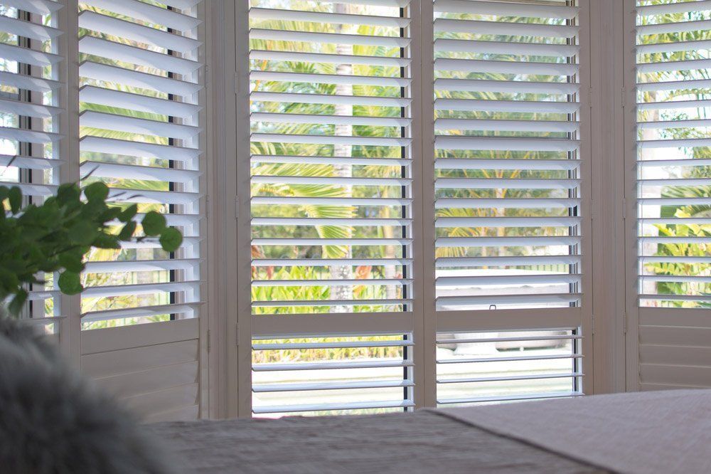 A Bedroom With White Shutters On The Windows — Summerland Screens & Awnings In Ballina, NSW