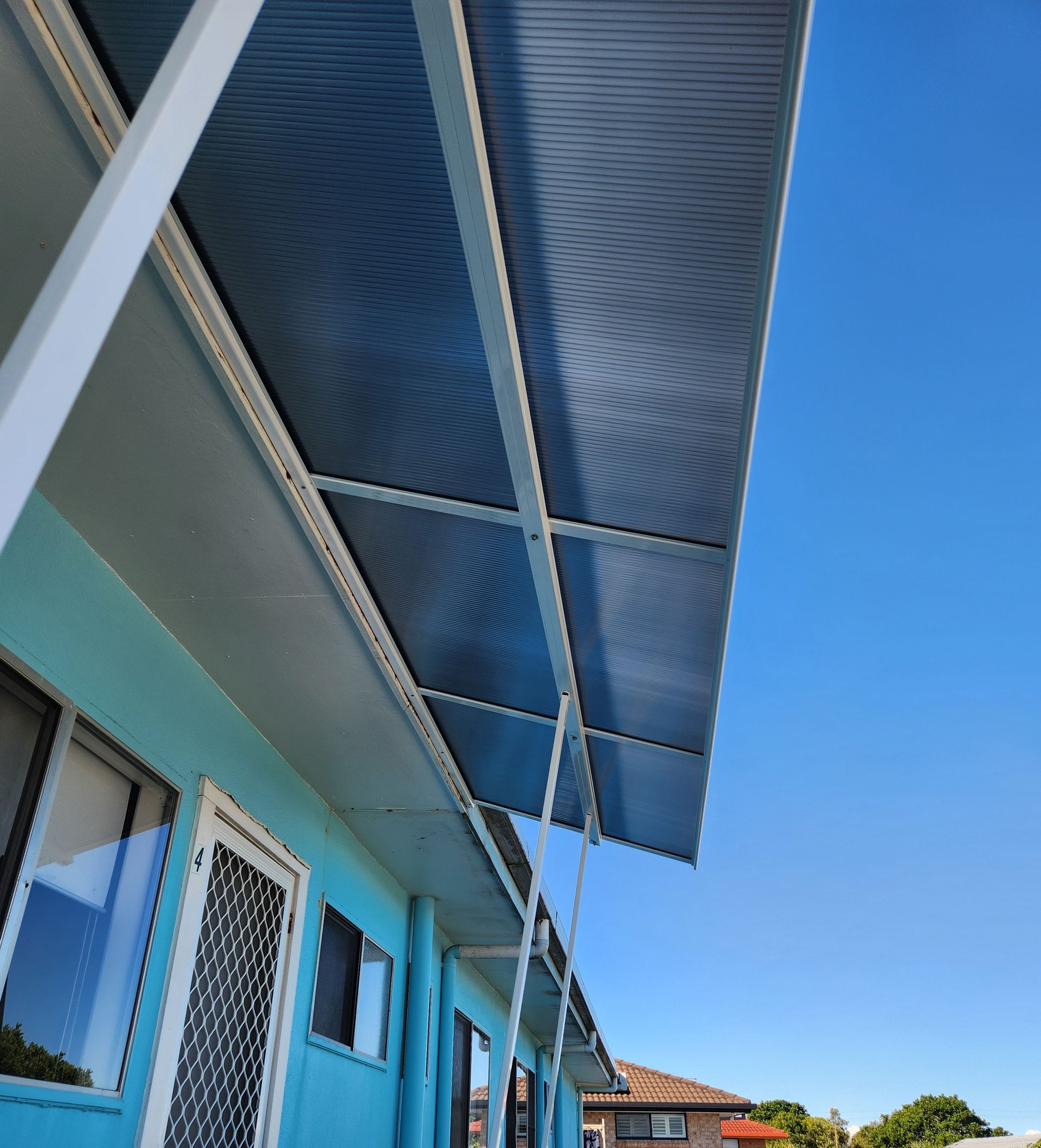 Blue Awning Over A Building With Blue Walls And White Trim Against A Clear Blue Sky — Summerland Screens & Awnings In Ballina, NSW