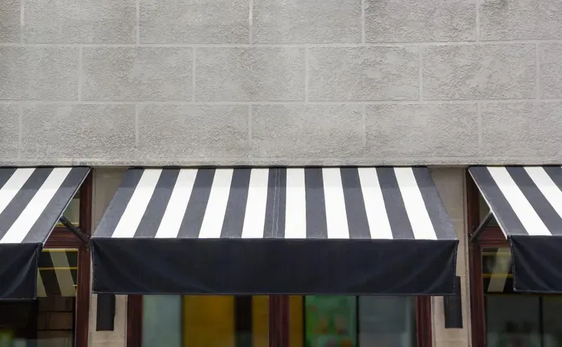 A Black And White Awning Is On The Side Of A Building — Summerland Screens & Awnings In Ballina, NSW