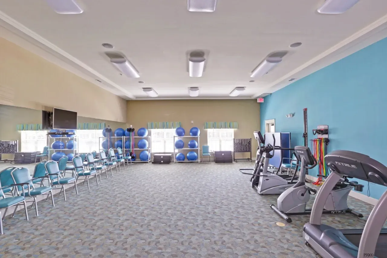 Interior of a community fitness center with treadmills, bikes, and free weights.