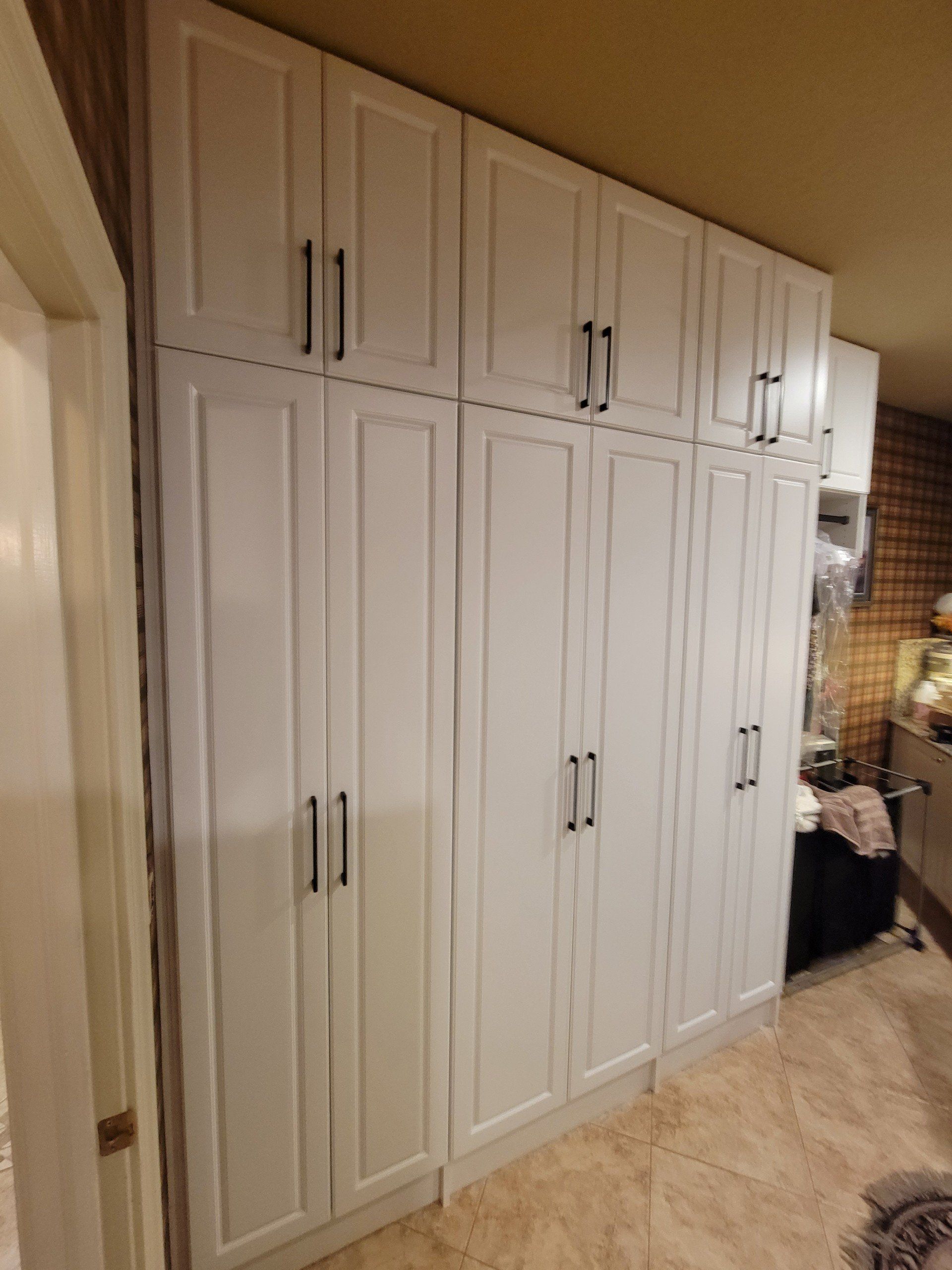 A kitchen with a lot of white cabinets and a tiled floor.