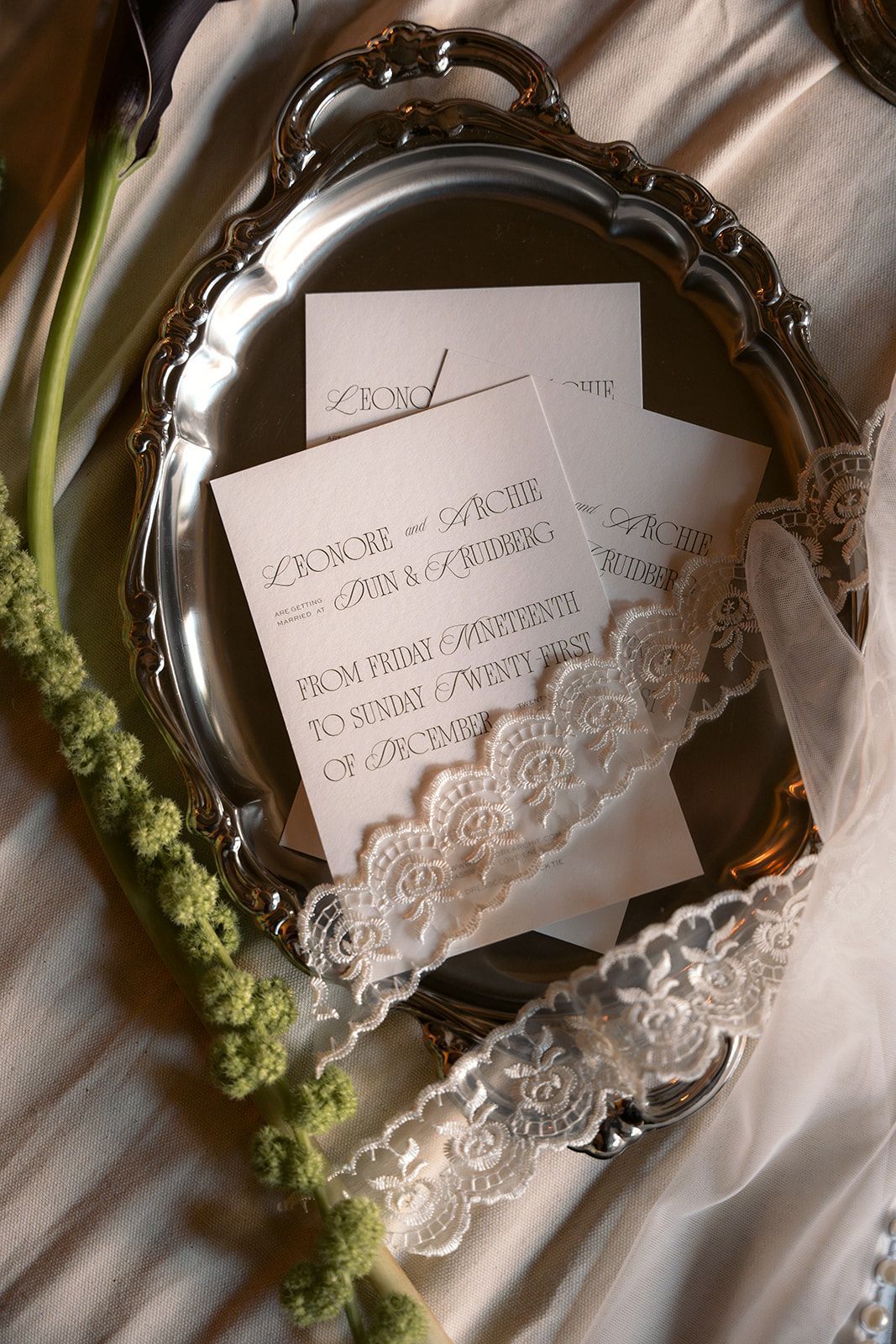 White lace garter with handwritten notes on a silver tray and white satin fabric